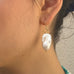 Cropped image of dark haired girl in profile looking to the left of the image and wearing Leoni & Vonk baroque pearl earrings.