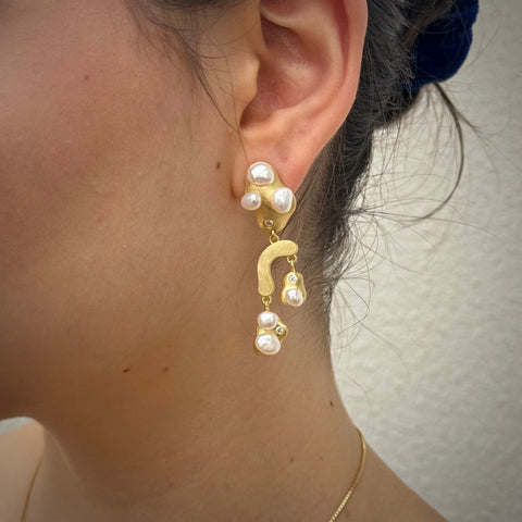 Cropped image of a dark haired girl wearing Leoni & Vonk gold and pearl drop earrings