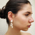 Dark haired girl looking to the side of the image wearing Leoni  & Vonk sterling silver and pearl drop earrings.