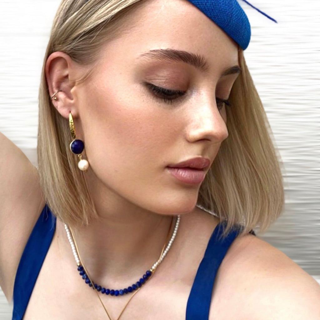 Blonde girl wearing a blue hat and Leoni & Vonk sapphire and lapis September's birthstone jewellery.