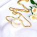 Leoni & Vonk pearl and gold bridal necklace on a white background with yellow roses