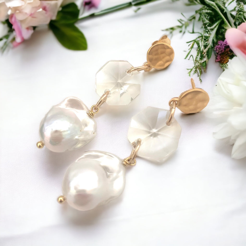 Leoni & Vonk vintage crystal and baroque pearl earrings on a white fabric background and with bridal flowers.