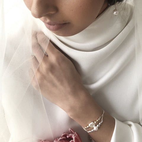 Image of a bride wearing Leoni & Vonk pearl bracelets. She has a hand up and you can only partially see her face.