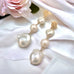 Leoni & Vonk long baroque earrings on white fabric with pink flowers