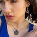 Dark haired girl wearing Leoni & Vonk vintage jewellery and a blue dress. She is looking to the side of the image and it is cropped to show her face and neck only.
