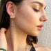 Dark haired girl looking to the side of the image wearing Leoni & Vonk citrine earrings
