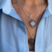 Image of a woman's neck. She is wearing a blue shirt and Leoni & Vonk vintage and antique jewellery