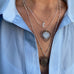Image of a woman's neck. She is wearing a blue shirt and Leoni & Vonk vintage and antique jewellery.