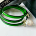 Leoni & Vonk emerald green leather bracelet with pearl and crystal charms on a white background and with Leoni & Vonk ribbon and box