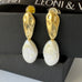 Leoni and Vonk gold and pearl earrings on a black box with Leoni & Vonk ribbon