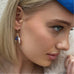 Blonde girl wearing a blue hat looking to the right of the image. She is wearing leoni  & Vonk pearl and September birthstone earrings.