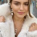 Dark haired girl looking our of the camera and wearing Leoni & Vonk pearl jewellery and a white fur coat.
