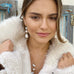 DArk haired girl looking out a the camera. She is wearing Leoni 7 Vonk pearl jewellery and a white fur cream coat.