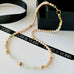 Leoni & Vonk pearl and gemstone necklace on a white background with Leoni & Vonk ribbon