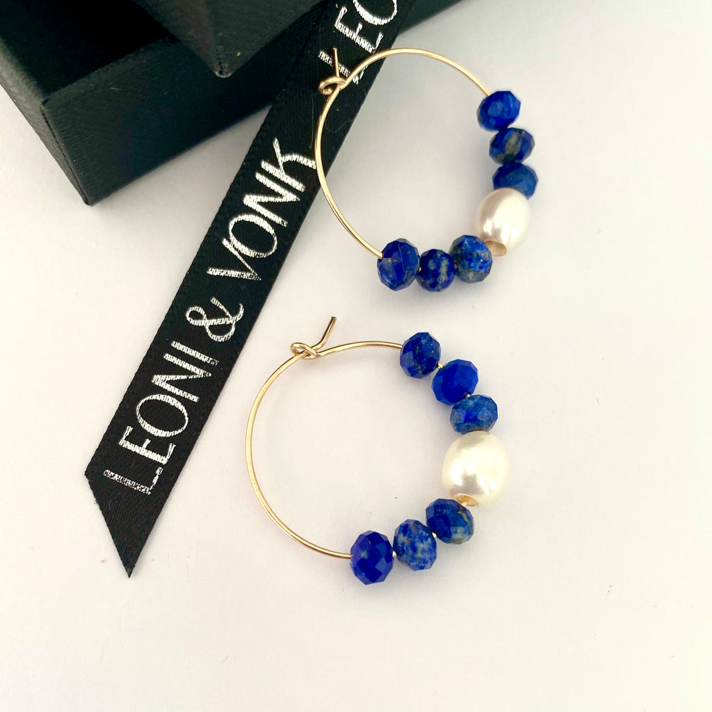Leoni & Vonk gold hoop, lapis and pearl earrings on a white background with Leoni & Vonk ribbon