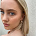 Blonde girl looking over her shoulder at teh camera. She is wearing Leoni & Vonk pink opal earrings.