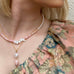 Blonde model wearing Leoni & Vonk pink opal and pearl jewellery and a floral top. The image is cropped so you can only see part of her face.Pink opal is one of October's birthstones.