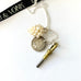 Leoni & Vonk antique watch key and 1868 threepence charm necklace on a white background with Leoni & Vonk ribbon