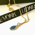 Leoni & Vonk gold and sapphire drop necklace on a white background and with Leoni & Vonk ribbon