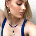 Blonde model wearing Leoni & Vonk September birthstone jewellery. She is looking to the right of the image and has her arm up.