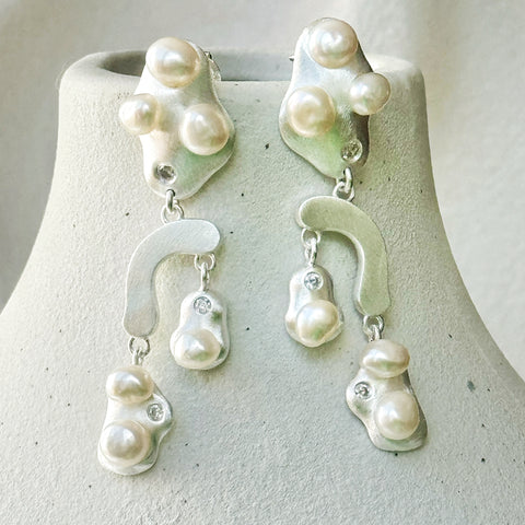Leoni & Vonk sterling silver pearl earrings hanging on a white vase