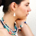Profile of a dark haired model wearing Leoni & Vonk multi gemstone and pearl jewellery