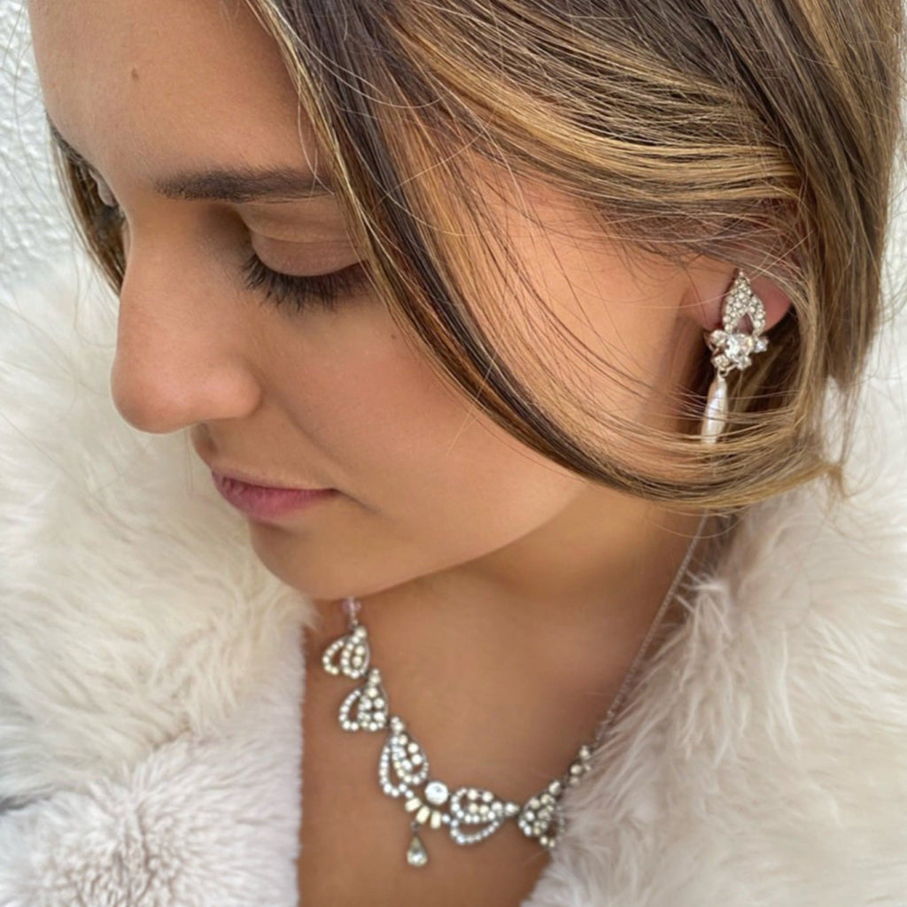 Dark haired girl looking down to the left of the image. She is wearing Leoni & Vonk vintage paste jewellery and a white fur coat.