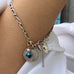 Image of woman's arm wearing Leoni & Vonk vintage sterling silver heart clasp bracelet featuring a 1944 British threepence 