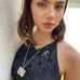 Dark haired girl looking to the side of the image. She is wearing an antique vesta case necklace and a blue dress.