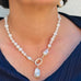 Cropped image of a dark haired woman wearing a dark blue top and Leoni & Vonk pearl jewellery