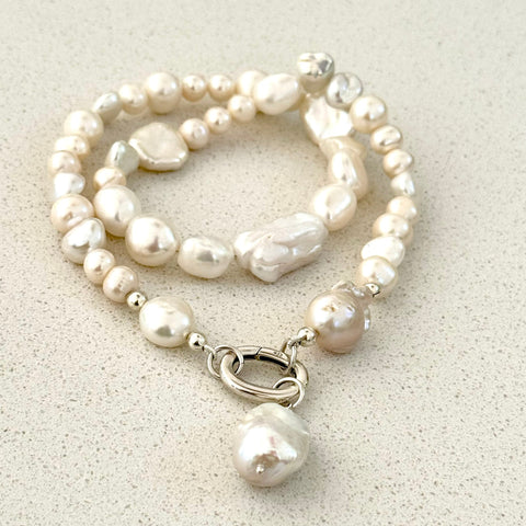 Leoni & Vonk luxe pearl necklace with sterling silver clasp on a white textured background