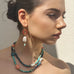 Dark haired model looking to the side of the image wearing Leoni & Vonk jewellery