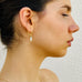 Dark haired girl;s profile showing she is wearing Leoni & Vonk gold huggie earrings