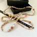 Leoni & Vonk pearl and crystal necklace in apricot hues on a white background with Leoni & Vonk ribbon and a bo