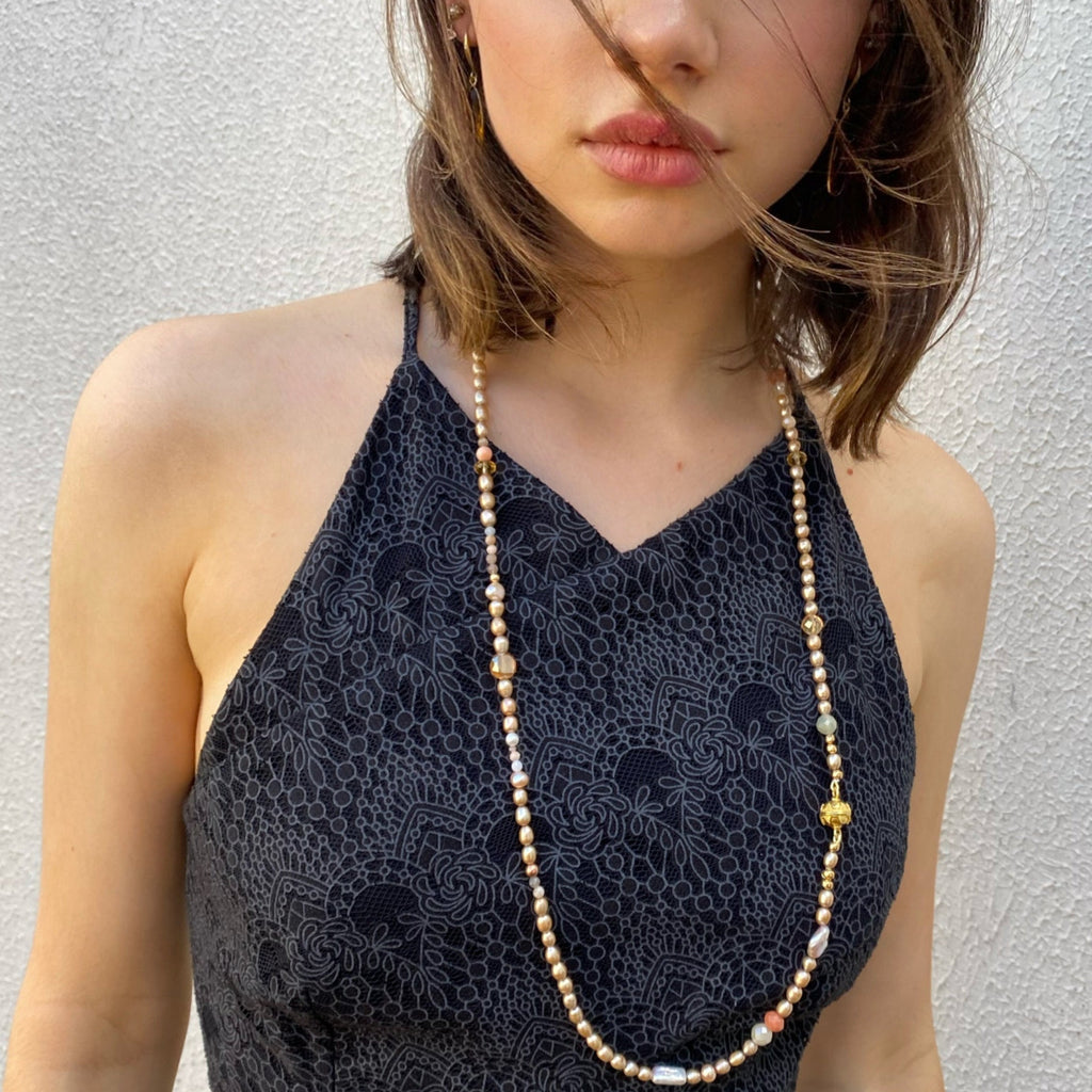Cropped image of a dark haired girl wearing a blue dress and Leoni & Vonk pearl necklace.