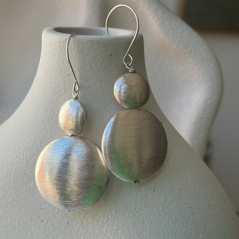 Leoni & Vonk sterling silver disc earrings on a white vase