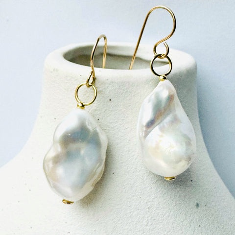 Leoni & Vonk baroque pearl earrings hanging on a white vase