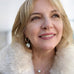 Blonde haired woman wearing Leoni & Vonk pearl jewellery and a cream fur coat. She is smiling and looking up wistfully.
