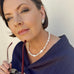 Dark haired woman wearing a dark blue top and Leoni & Vonk pearl jewellery