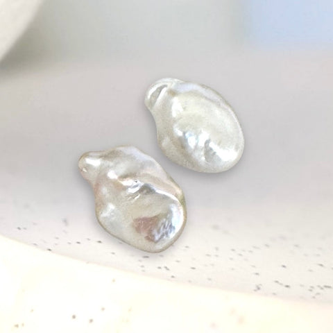 Leoni & Vonk white baroque pearl stud earrings on a textured background