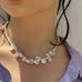 Cropped image of a dark haired girl wearing white sunglasses and Leoni & Vonk jewellery. She is also wearing a lilac shirt and is looking to the left of the image