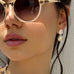 Dark haired girl looking to the left of the image wearing Leoni & Vonk pearl earrings and white sunglasses