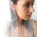 Dark haired bride wearing Leoni & Vonk bridal keshi pearl earrings. She is wearing a veil and looking to the side of the frame.