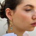 Dark haired model wearing Leoni & Vonk charm earrings. She is looking to the side of the image.