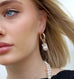 Blonde girl with blue eyes looking to the side of the image wearin Leoni & Vonk pearl earrings and necklace
