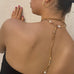 Back of dark haired girl wearing Leoni & Vonk leather and pearl necklace and gold hoop earring.