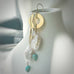 Leoni and Vonk gold, pearl and howlite earrings on a white vase