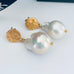 Leoni & Vonk gold stud earrings with white baroque pearl drops on a white background.