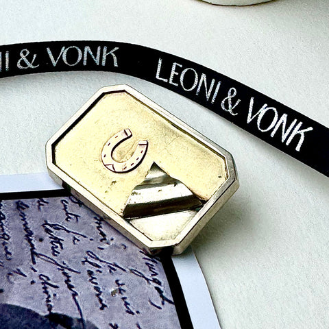 Leoni & Vonk antique horseshoe brooch on a white background with Leoni & Vonk ribbon