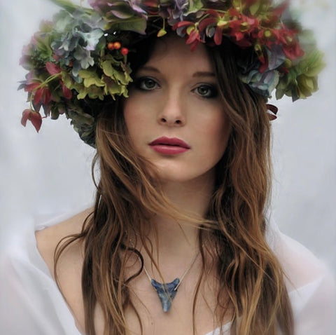 Image of dark haired model with flowers in her hair wearing Leoni  & Vonk lapis wolf head necklace